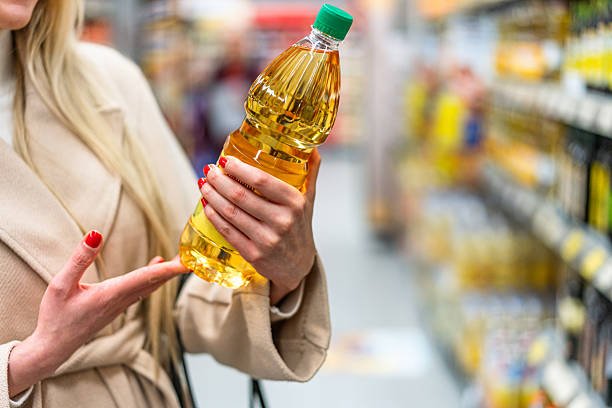 Woman shopping in the supermarket, she's choosing some sunflower oil from the shelf